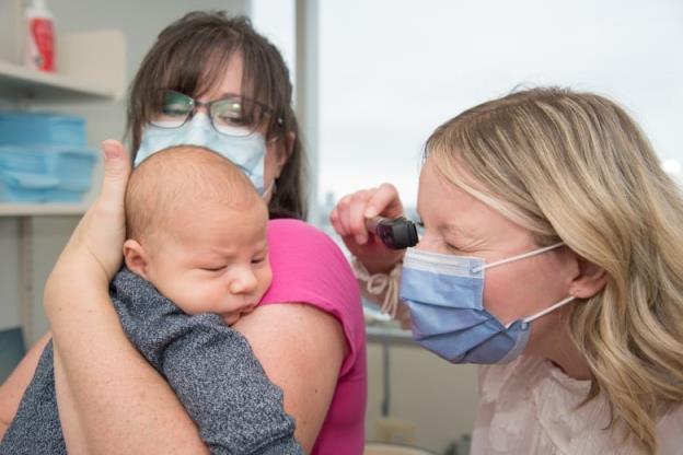 Midwife Annie Latham giving a newborn a medical checkup while he's in his mom Allison's arms. 