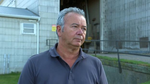 A man with short hair wears a polo shirt and looks off camera.