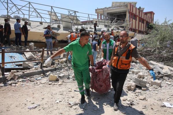 Paramedics carry a body from the site of an Israeli strike on a school, housing displaced Palestinians, in the Rimal neighbourhood of central Gaza City on August 20, 2024, amid the o<em></em>ngoing co<em></em>nflict between Israel and the militant Hamas group. (Photo by Omar AL-QATTAA / AFP)