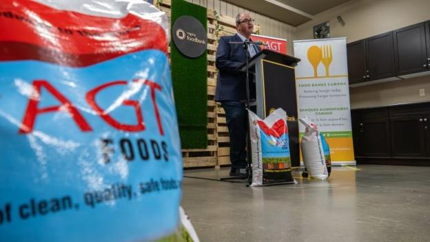 A bag marked AGT Foods with a man standing at a podium in the background