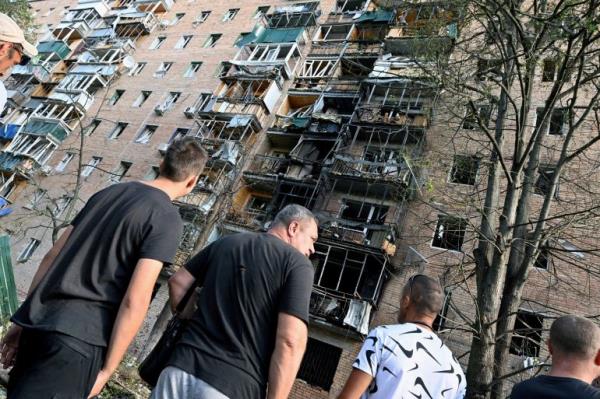 FILE PHOTO: People gather in the courtyard of a multi-storey residential building, which according to local authorities was hit by debris from a destroyed Ukr<a href=